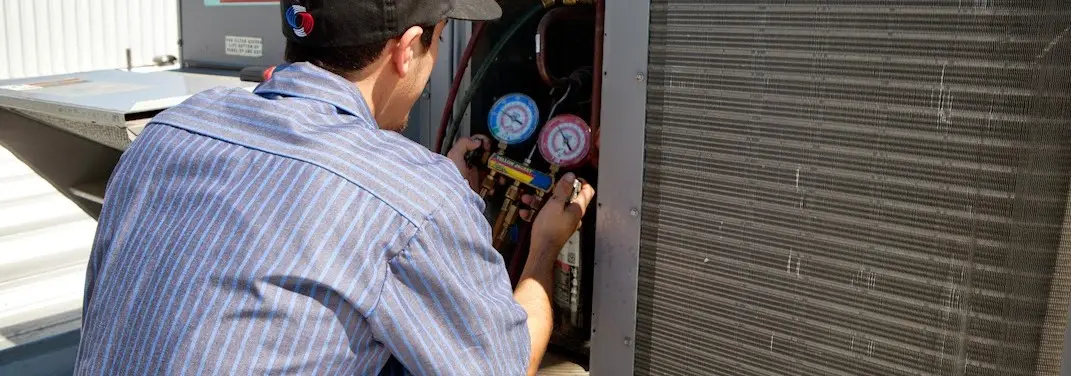 HVAC technician servicing a condenser unit in Marion